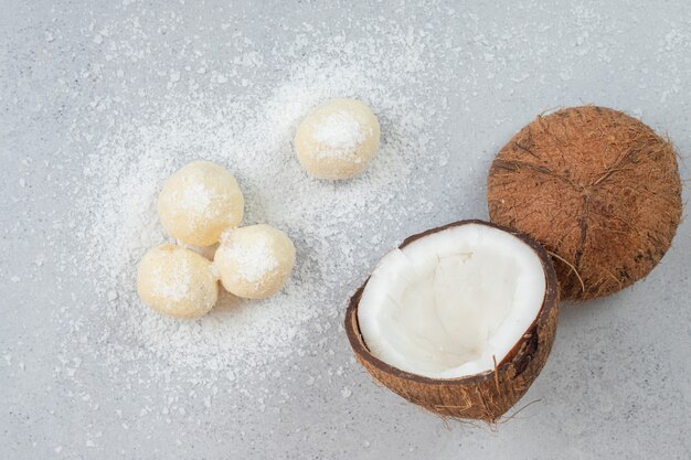 Geschnittene Kokosnuss mit runden süßen Keksen auf weißer Oberfläche