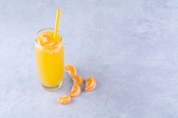 Geschnittene Mandarine und ein Glas saftig, auf dem Marmorhintergrund.