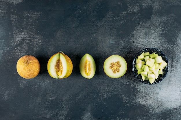 Geschnittene Melonen mit Melone in einer schwarzen Schüssel Draufsicht auf einem dunklen hölzernen Hintergrund kopieren Raum für Text