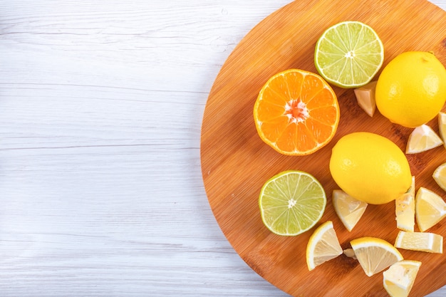Geschnittene orange Frucht der grünen und gelben Zitrone auf frischen Zitronen des Schneidebretts auf weißer Tabelle