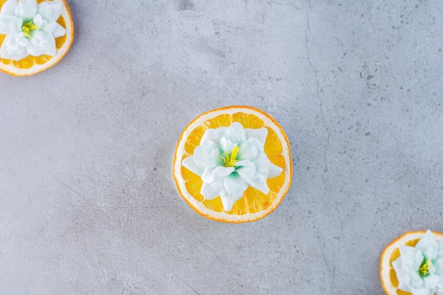 Geschnittene Orangenfrucht mit weißen Blüten auf Grau