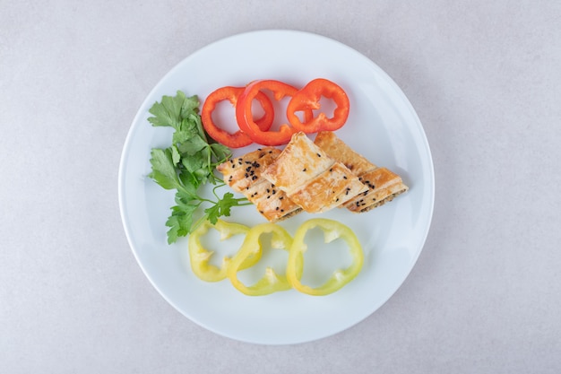 Geschnittene Paprika, Petersilie und Pfannkuchen mit Fleisch auf Teller, auf dem Marmor.