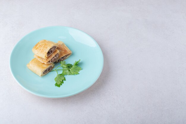 Geschnittene Pfannkuchen mit Fleisch auf Teller, auf dem Marmor.