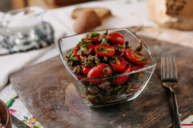 geschnittene rote Tomaten zusammen mit braunem Bohnengrün auf rustikalem Schreibtisch aus braunem Holz