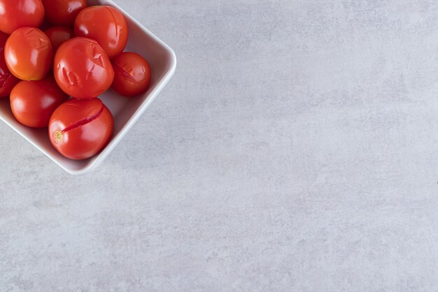 Geschnittene salzige Tomaten in der Holzschale, die auf Steinhintergrund gelegt wird.