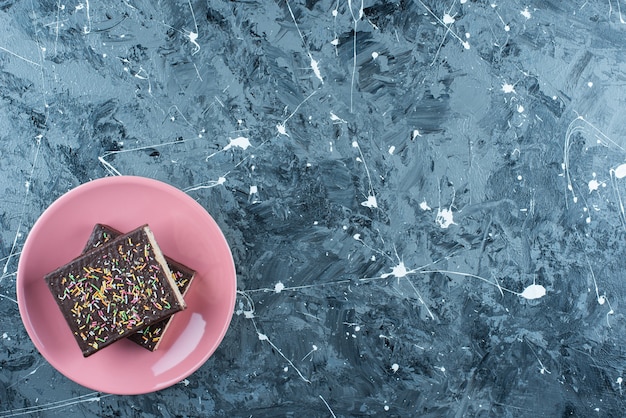 Geschnittene schokoladenbeschichtete Waffel auf einem Teller auf dem blauen Tisch.