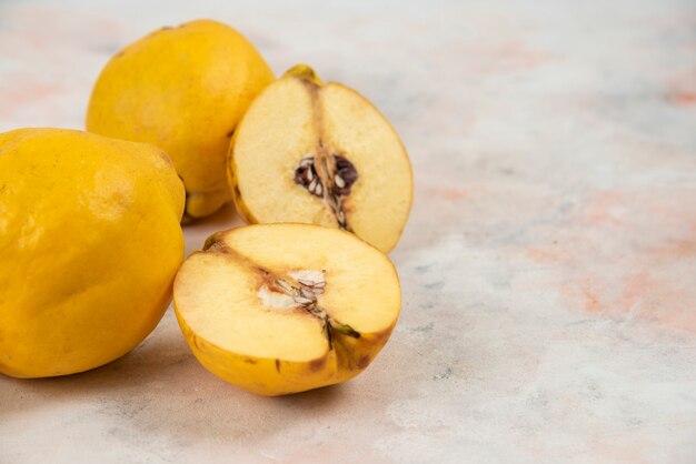 Geschnittene und ganze frische Quittenfrüchte auf Marmortisch.