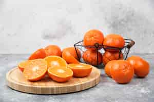 Kostenloses Foto geschnittene und ganze saftige frische orangenfrüchte auf einen steintisch gelegt.