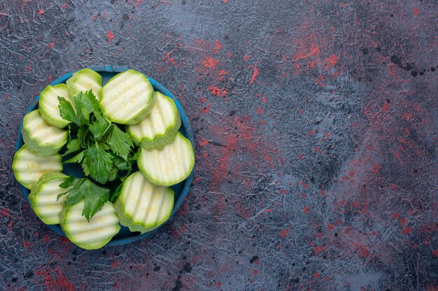 Geschnittene Zucchini mit Petersilie in einer blauen Platte.