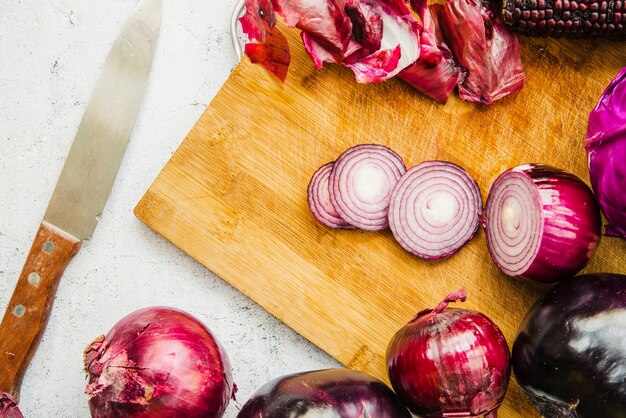 Geschnittene Zwiebel mit Gemüse auf hackendem Brett nahe Messer