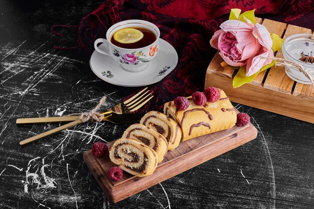 Geschnittener Brötchenkuchen mit Schokoladenfüllung, serviert mit einer Tasse Tee.