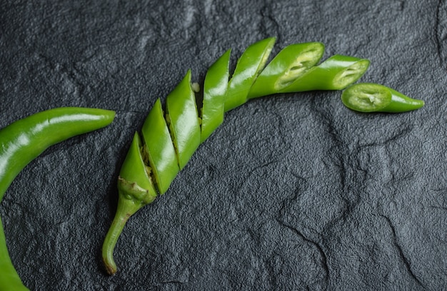 Kostenloses Foto geschnittener grüner jalapenopfeffer auf einem schwarzen tisch