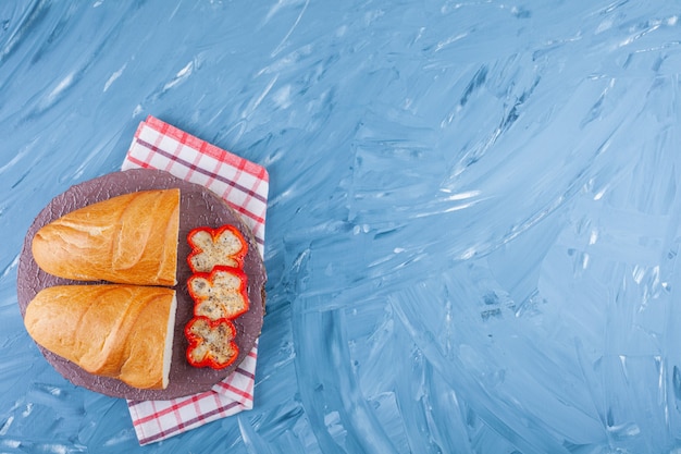 Geschnittener Pfeffer und Brot an Bord auf Geschirrtuch, auf blau.