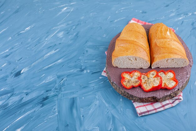 Geschnittener Pfeffer und Brot auf einem Brett auf einem Geschirrtuch, auf dem Blau.