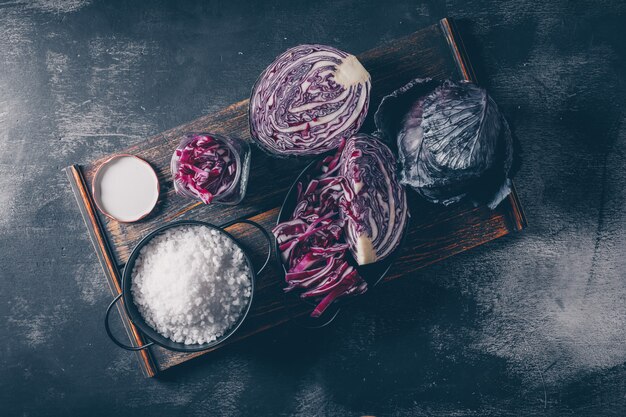 Geschnittener und gehackter Rotkohl auf einem Serviertablett auf einem dunklen strukturierten Hintergrund. Draufsicht.