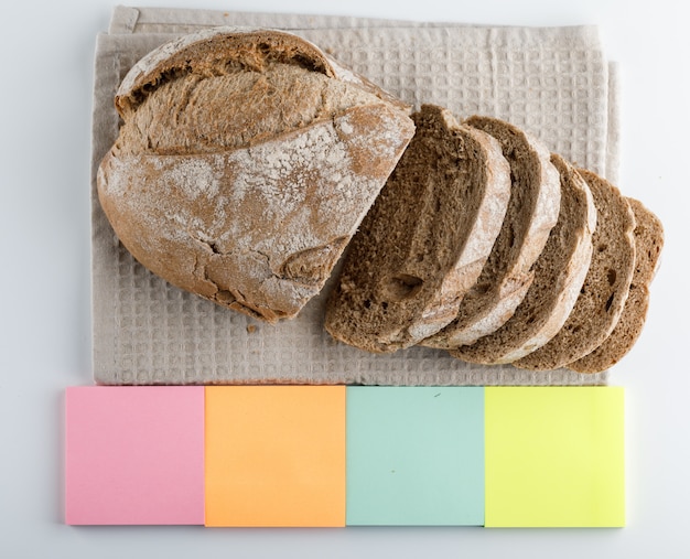 Geschnittenes Brot mit Seitenansicht der bunten Haftnotizen auf einer weißen Oberfläche
