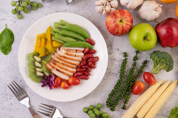 Geschnittenes Hühnersteak mit Erbsen, Tomaten, Kiwi und Kürbis.