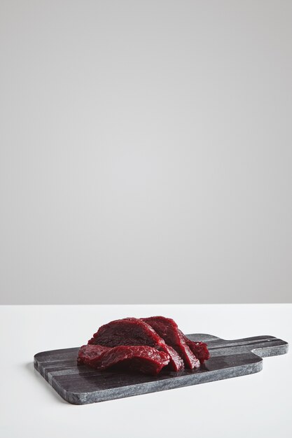 Geschnittenes Premium rohes Walfleischsteak auf Marmorsteinschneidebrett lokalisiert auf weißem Tisch