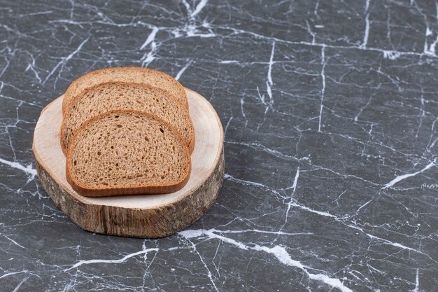 Geschnittenes Roggenbrot auf Holzbrett über grau.