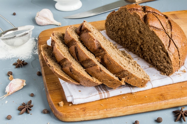 Geschnittenes Roggenbrot auf Tuch auf Tabelle mit Gewürzen