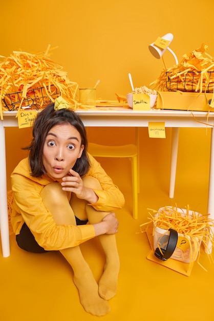 Kostenloses Foto geschockte studentin erfährt von der frist für die prüfungsvorbereitung sitzt auf dem boden unter dem desktop im coworking space hört schockierende nachrichten studien von zu hause bereitet sich auf die prüfungssitzung vor