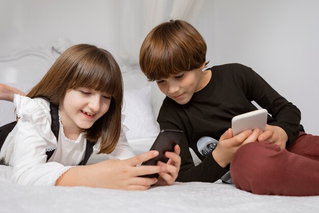 Geschwister im Schlafzimmer mit Telefon