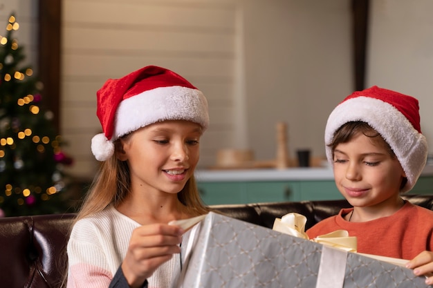 Kostenloses Foto geschwister öffnen gemeinsam ein weihnachtsgeschenk