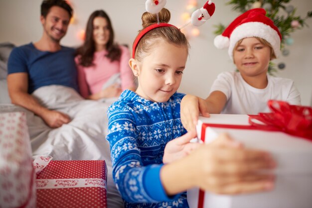 Geschwister öffnen Weihnachtsgeschenk im Bett