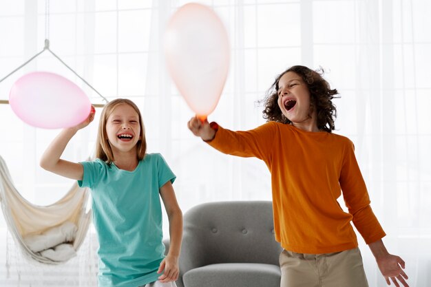 Geschwister spielen zu Hause mit Luftballons