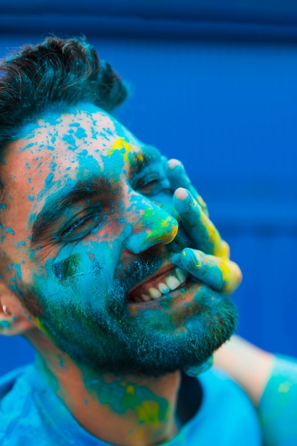 Gesicht des Mannes befleckte blaues Pulver auf Holi-Festival