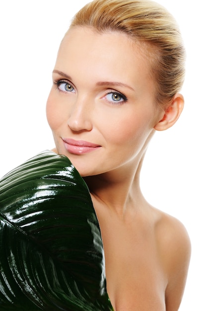 Gesicht einer jungen Gesundheitsfrau mit dem grünen Blatt