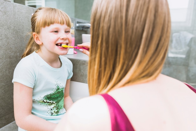 Kostenloses Foto gesichtslose mutter, die zähne der tochter putzt