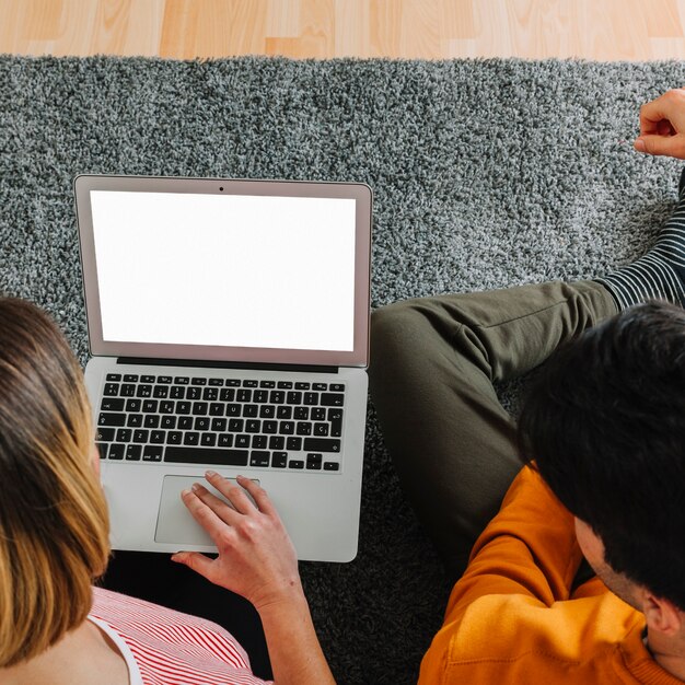 Gesichtslose Paare, die Laptop auf Boden verwenden