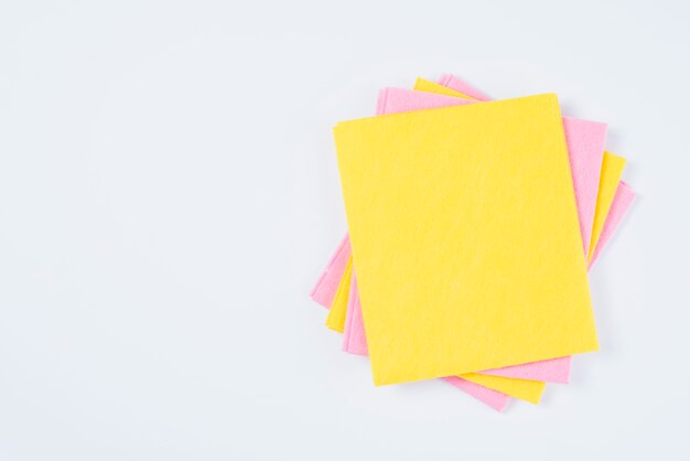 Gestapelte gelbe und rosa farbige Staubtücher auf weißem Hintergrund