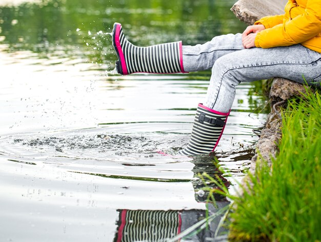 Gestreifte Gummistiefel im Fluss mit Spritzwasser. Frühling im Dorf.