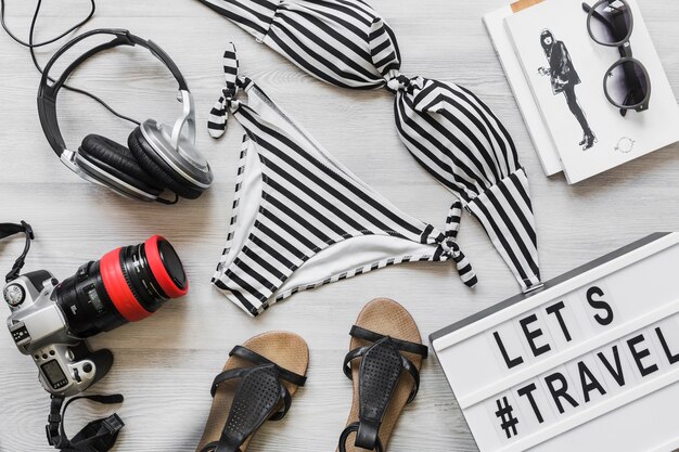 Gestreifter weiblicher Bikinibadeanzug mit reisendem Zubehör auf Schreibtisch
