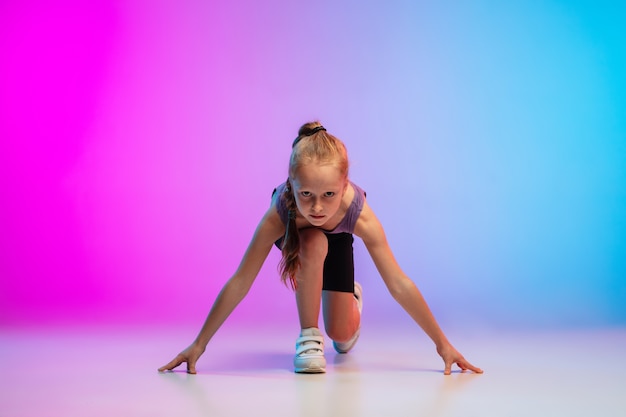 Gesund. Teenager-Mädchen, professioneller Läufer, Jogger in Aktion, Bewegung lokalisiert auf Gradienten-rosa-blauem Hintergrund im Neonlicht. Konzept von Sport, Bewegung, Energie und dynamischem, gesundem Lebensstil.