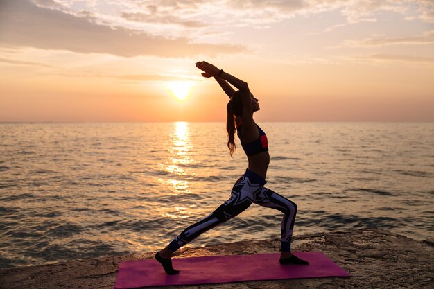 Gesunde attraktive Frau, die Übungen für Körper, übendes Yoga tut