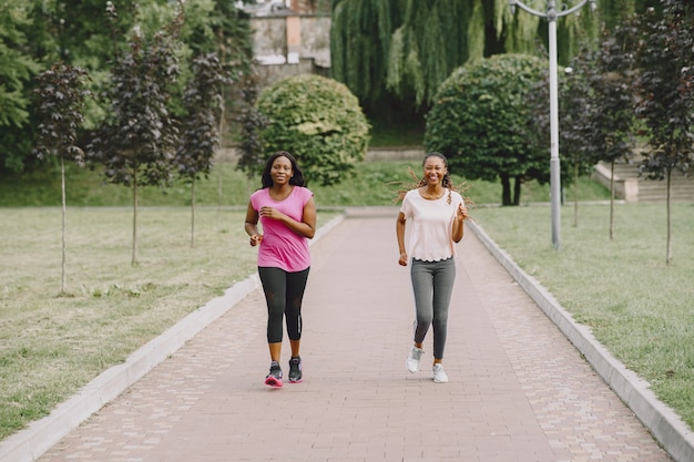 Gesunde junge afrikanische Frauen draußen im Morgenpark. Freunde trainieren.