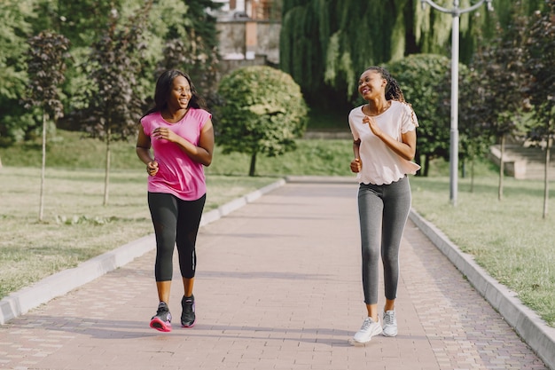 Gesunde junge afrikanische Frauen draußen im Morgenpark. Freunde trainieren.