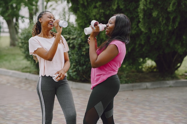 Gesunde junge afrikanische Frauen draußen im Morgenpark. Freunde trainieren.