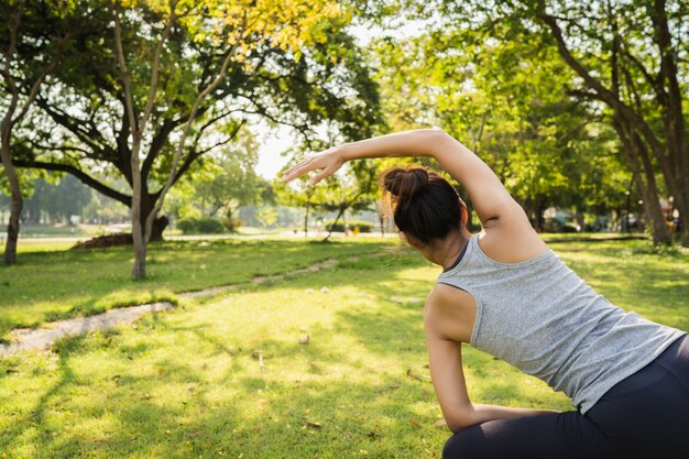 Gesunde junge asiatische Läuferfrau wärmen den Körper auf, der vor Übung und Yoga ausdehnt