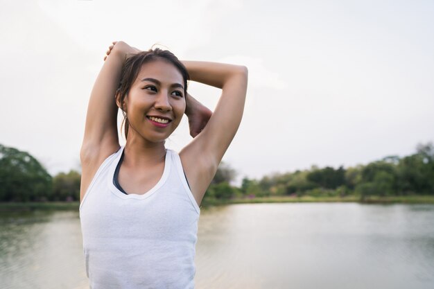 Gesunde junge asiatische Läuferfrau wärmen den Körper auf, der vor Übung und Yoga ausdehnt