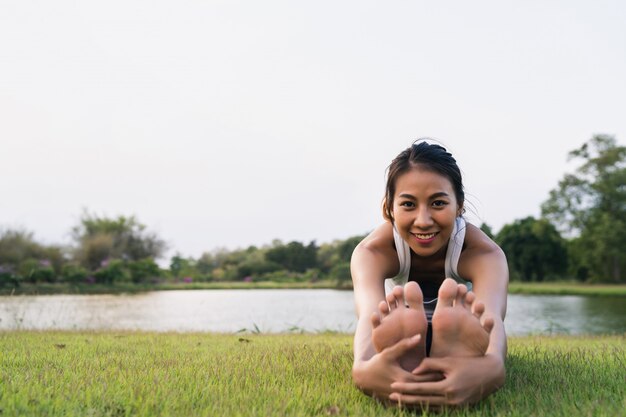 Gesunde junge asiatische Läuferfrau wärmen den Körper auf, der vor Übung und Yoga ausdehnt