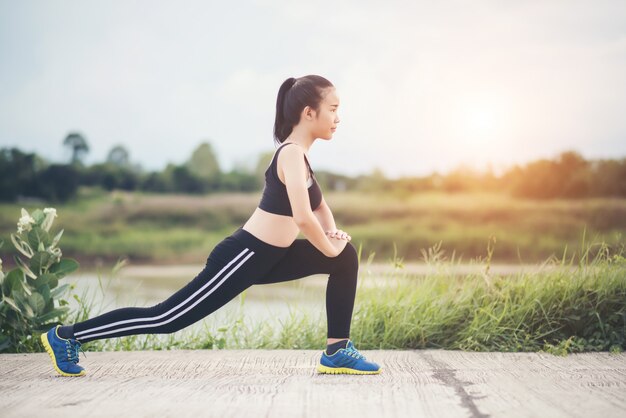 Gesunde junge Frau, die draußen Training vor Trainingssitzung am Park aufwärmt.