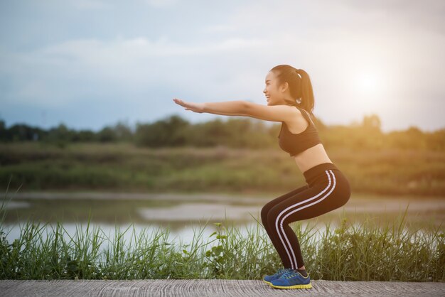 Gesunde junge Frau, die draußen Training vor Trainingssitzung am Park aufwärmt.