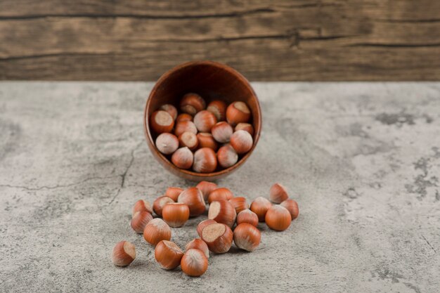 Gesunde Macadamia-Nüsse in der Schale auf einem Steinhintergrund.