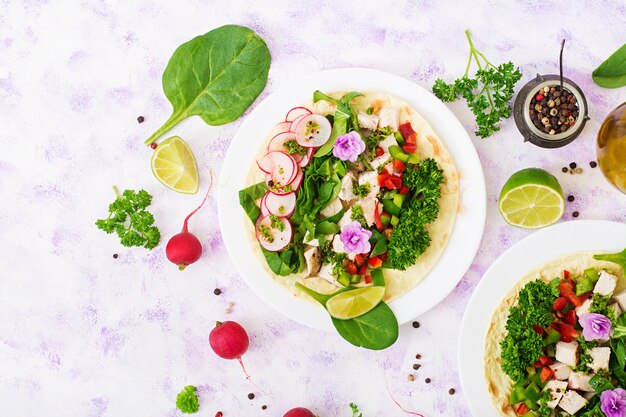 Gesunde mexikanische Maistacos mit gekochter Hühnerbrust, Spinat, Rettich und Paprika