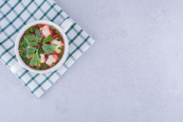 Gesunde Portion Blumenkohlsuppe in einer kleinen Schüssel auf gefalteter Tischdecke auf Marmorhintergrund. Foto in hoher Qualität