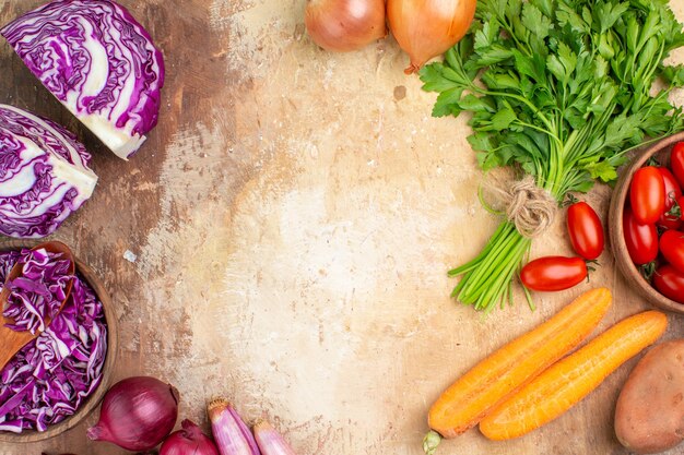 Gesunde Salatzutaten von oben, hergestellt aus einem Rotkohlbündel Petersilie-Roma-Tomaten, Karottenkartoffeln und Zwiebeln auf einem hölzernen Hintergrund mit freiem Platz für Text